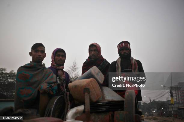Laborers stand on a vehicle as they go work at a early winter morning in Dhaka, Bangladesh on Friday, December 18, 2020.