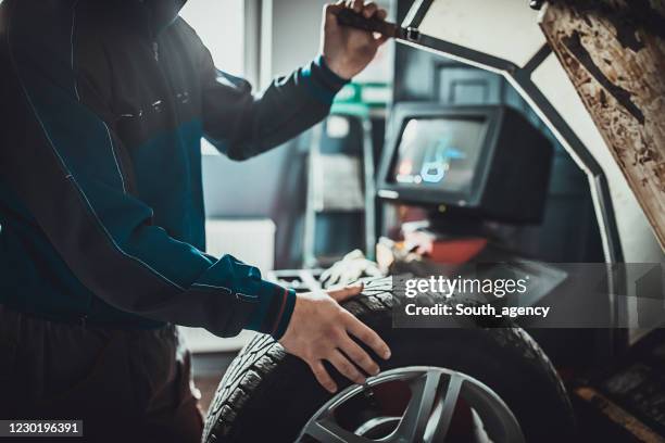 werktuigkundige die een band in autoreparatiewerkplaats in evenwicht brengt - automotive technician stockfoto's en -beelden