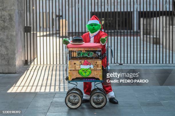 An organ grinder in a Grinch costume plays in downtown Mexico City on December 18, 2020 as cases of COVID-19 increase amid the novel coronavirus...