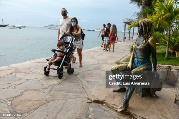 Tourists walk next to a Brigitte Bardot statue at Orla Brigitte Bardot after the decision of the Rio de Janeiro State Justice to reverse the closure...