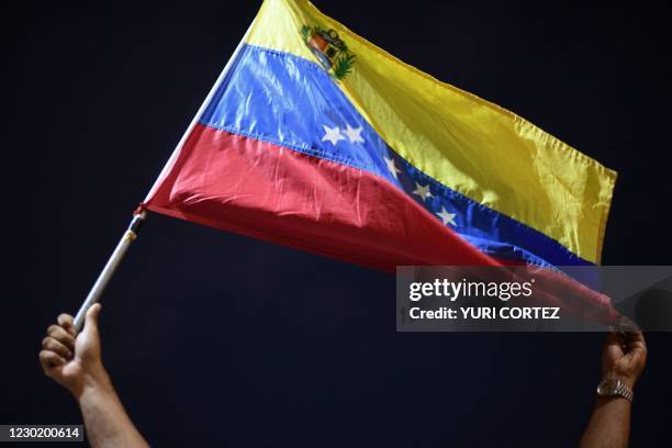 Man displays a Venezuelan flag as relatives and friends of 28 Venezuelan migrants who died when a boat transporting them to Trinidad and Tobago sank,...