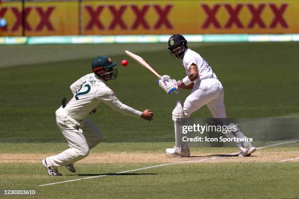 Virat Kohli Captain of India hits the ball and Travis Head of Australia nearly takes a catch during day three of the First Vodafone Test cricket...