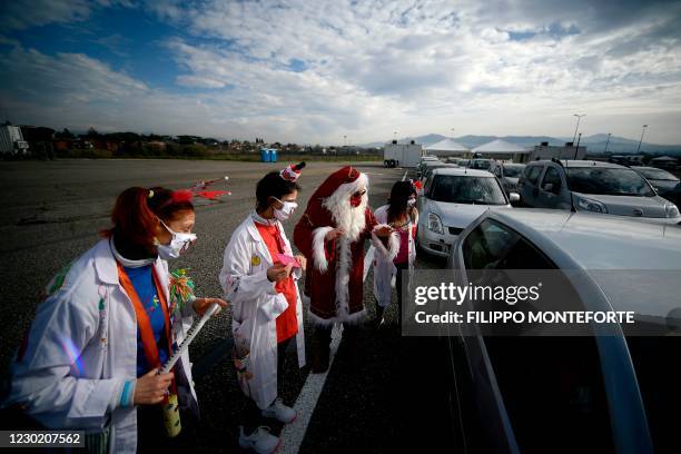Medical workers dressed as clowns and Santa Claus entertain people lined up in their car to undergo a COVID-19 swab test for coronavirus, on December...
