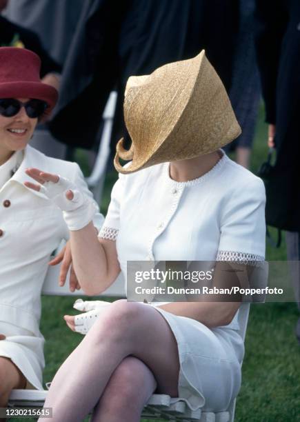 English fashion editor Isabella Blow attending an event wearing a flamboyant hat, circa 1990.