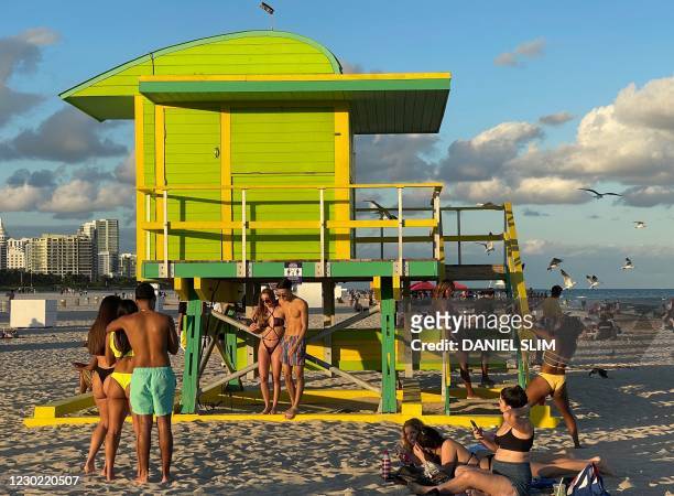 Beachgoers take selfies in front of a colorful lifeguard station on December 19, 2020 in South Beach, Florida amid the coronavirus pandemic.