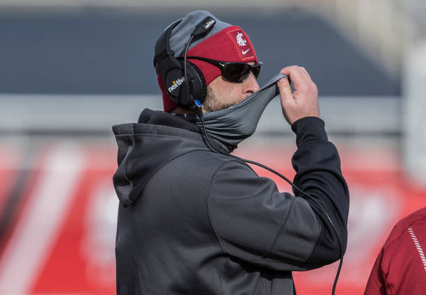 Nick Rolovich head coach of the Washington State Cougars adjusts his mask during their game against the Utah Utes on December 19, 2020 at Rice Eccles...