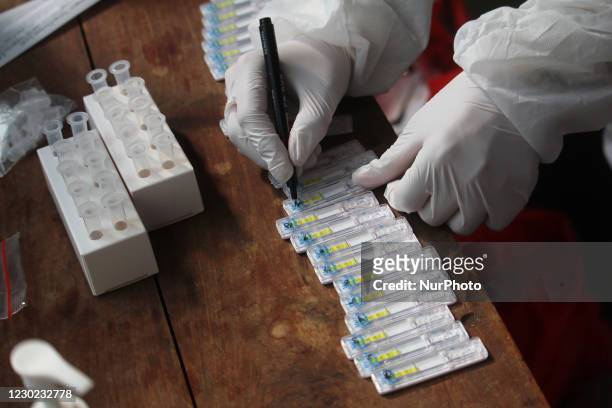 Healthcare worker writes the date on a rapid antigen detection testing kit during a medical check-up for COVID-19 pandemic at a railway station in...