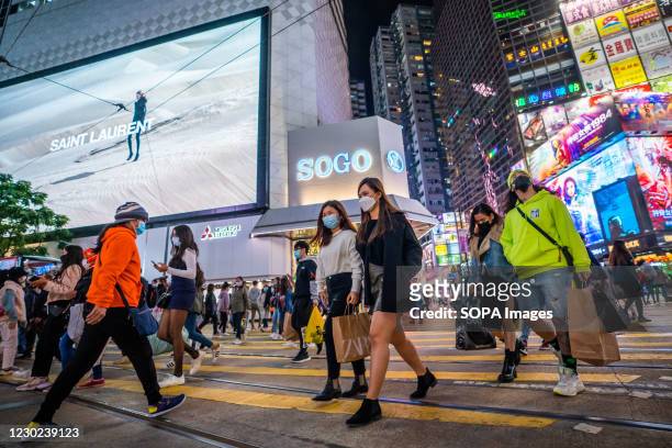 People wearing facemasks as preventive measure against the spread of Covid-19 coronavirus cross the road at a zebra crossing outside the SOGO...