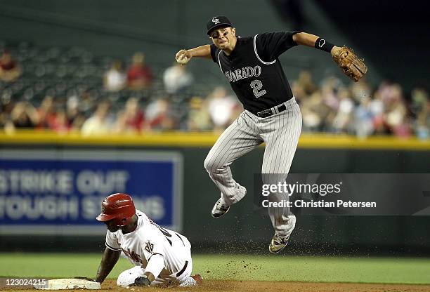 Infielder Troy Tulowitzki of the Colorado Rockies throws over the sliding Justin Upton of the Arizona Diamondbacks to complete a double play during...