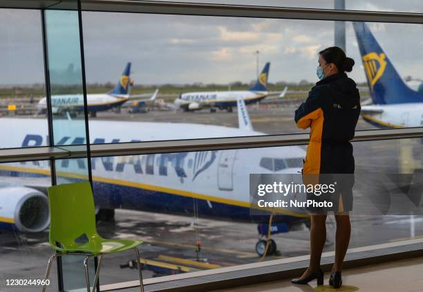 Member of Ryanair cabin crew looks out of the window at Ryanair planes grounded at Dublin Airport . From midnight all flights and passenger ferries...