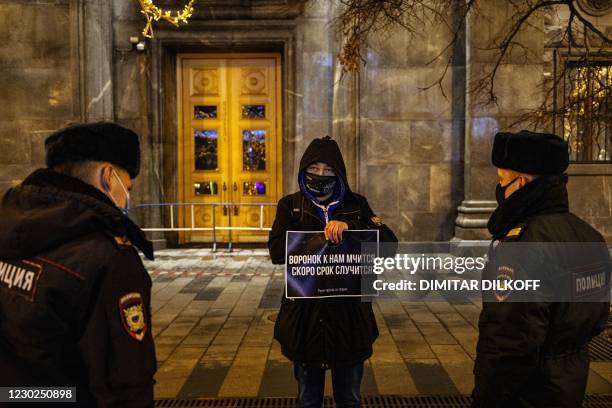 Supporter of opposition leader Alexei Navalny holding a placard reading "A police wagon rushes towards us, someone's getting a prison term soon"...