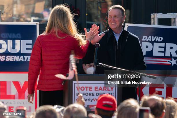 Senators Kelly Loeffler and David Perdue high five each other as Perdue takes the stage to speak during a campaign event on December 21, 2020 in...