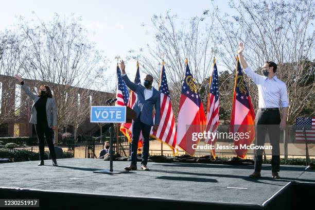 Vice President-elect Kamala Harris with Georgia Democratic Senate candidates Rev. Raphael Warnock and Jon Ossoff wave to the crowd during a drive-in...