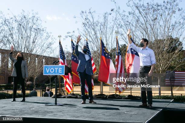 Vice President-elect Kamala Harris with Georgia Democratic Senate candidates Rev. Raphael Warnock and Jon Ossoff wave to the crowd during a drive-in...