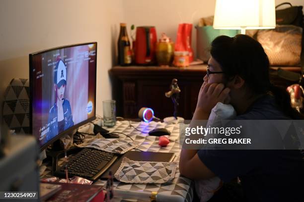 In this photo taken on November 14 fan Liu Jun watches an episode of virtual idol talent show "Dimension Nova" featuring his favourite idol Amy, at...