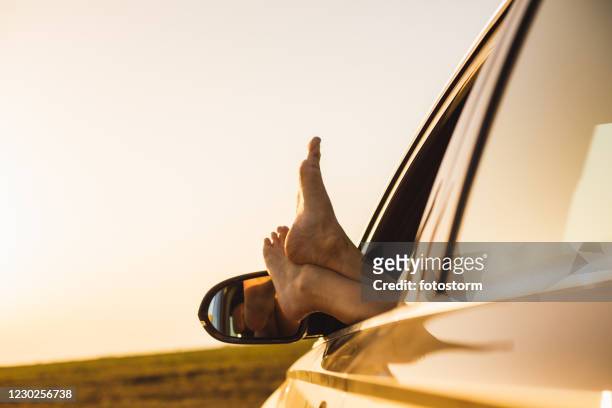 ruhen sie ihre füße auf dem autofenster und genießen sie den sonnenuntergangblick - car mirror stock-fotos und bilder