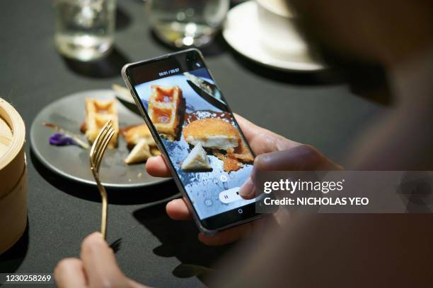 Guest uses a mobile phone to take a video of a meal featuring a nugget made from lab-grown chicken meat during a media presentation in Singapore, the...