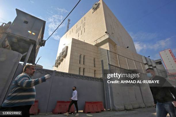 People walk past the Central Bank of Iraq headquarters along Rashid Street in the centre of Iraq's capital Baghdad on December 22, 2020. - Hundreds...