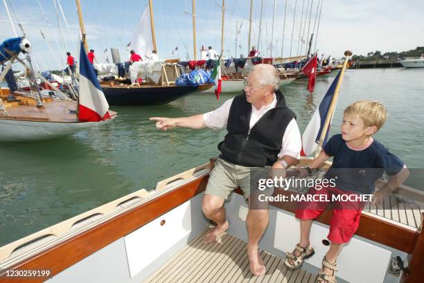 Photographe et peintre de la Marine Philip Plisson et son petit-fils Marin sont à la barre d'un petit canot breton le 17 Juin 2003 dans le port de la...