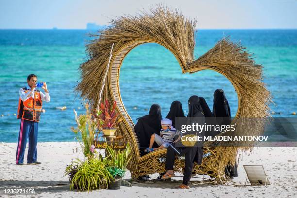 Man takes photos of a group of Muslim women wearing niqabs on a beach on Koh Lipe island on December 23, 2020.