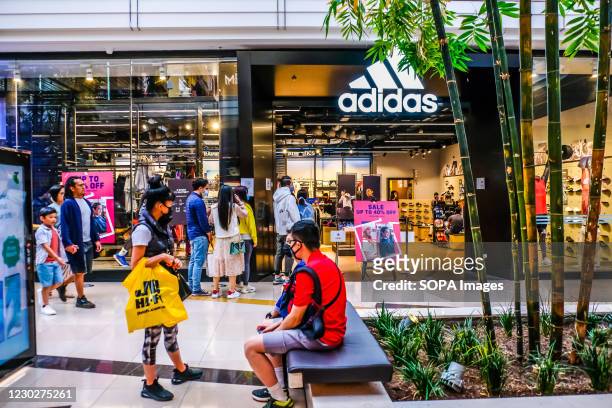 Man sitting outside while others lining up at Adidas store during Christmas shopping in Chadstone Shopping Centre - The Fashion Capital of Melbourne.