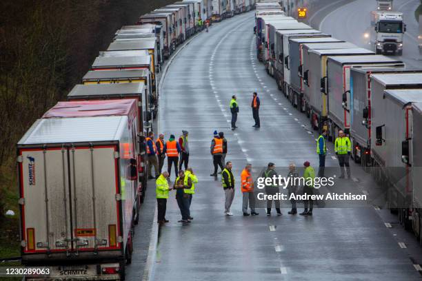 Drivers mingle out of their cabs as their freight lorries line up in queues contained in Operation Stack on the M20 motorway at Ashford, Kent, United...