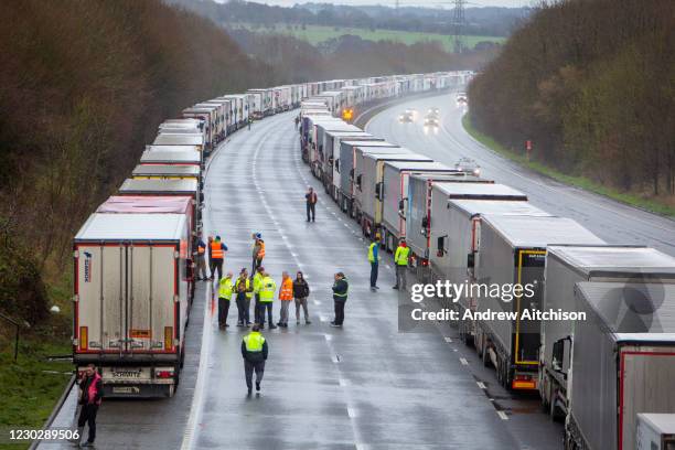 Drivers mingle out of their cabs as their freight lorries line up in queues contained in Operation Stack on the M20 motorway at Ashford, Kent, United...