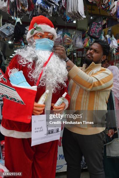 Man put a face mask on a santa claus for sale ahead of Christmas amid coronavirus outbreak, at Chhota Mall, Sigra road on December 24, 2020 in...