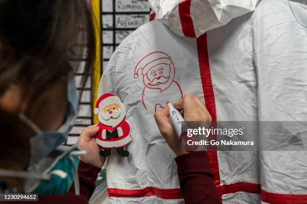 Medical staff member Anne Aguilar draws a Santa Claus figure on a coverall suit in the nursing station of the COVID-19 intensive care unit on...