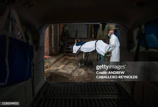 Maryland Cremation Services transporter Reggie Elliott brings the remains of a Covid-19 victim to his van from the hospital's morgue in Baltimore,...