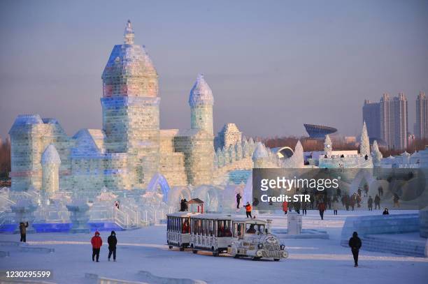 This photo taken on December 24, 2020 shows tourists looking at ice sculptures ahead of the Harbin International Ice and Snow Festival in Harbin, in...