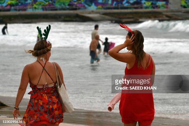 People wearing festive antlers enjoy a walk along the almost empty Bondi Beach on Christmas Day in Sydney on December 25 as the Covid-19 coronavirus...