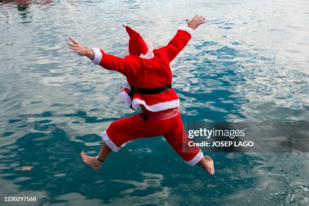 Participant in a Santa Claus costume jumps into the water during the 111th edition of the Copa Nadal swimming race in Barcelona's Port Vell on...