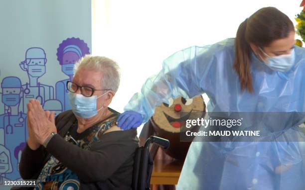 This video grab shows Josefa Perez a resident of Feixa Llarga nursing home for the elderly celebrating after receiving a dose of the Pfizer-BioNTech...