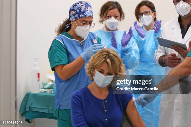 Nurses cheer after a woman is injected with the first dose of Pfizer-Biontech vaccine, against the Coronavirus COVID-19 virus, in the vaccination...