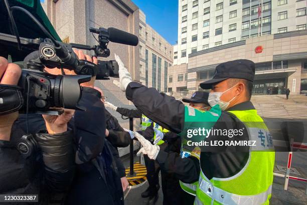 Policeman covers a camera to stop journalists from recording footage outside the Shanghai Pudong New District People's Court, where Chinese citizen...