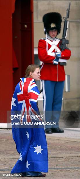 Girl draped in an Australian flag walks past a Royal guard at Amalienborg castle in Copenhagen 14 May 2004, before Australian Miss Mary Elizabeth...