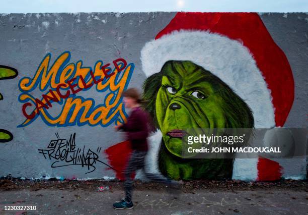 Mural painting by graffiti artist Eme Freethinker features a likeness of US author Dr Seuss' Grinch character with a "cancelled" stamp across a Merry...