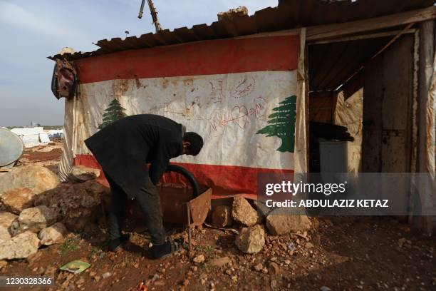 Displaced Syrian who gave his first name as Mahmud works outside his makeshift tyre repair shop which he covered with a Lebanese flag following...