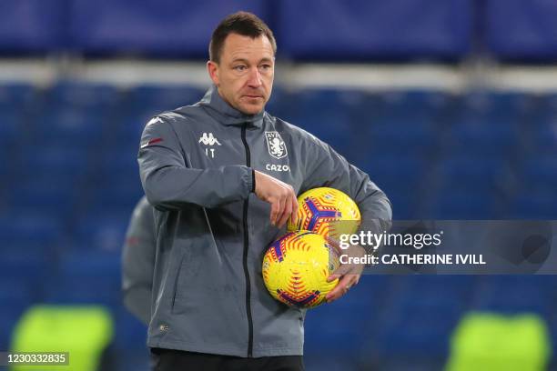 Aston Villa's English assistant coach John Terry collects up the balls ahead of the English Premier League football match between Chelsea and Aston...