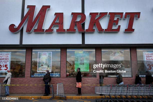 Shoppers wait in line outside a Market Basket in Somerville, MA on December 26, 2020. New state restrictions aimed at reducing the spread of COVID-19...