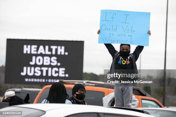 Blake Christopher holds a handmade sign during a "It's Time to Vote" drive-in rally for Georgia Democratic Senate candidates Raphael Warnock and Jon...