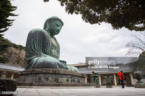 Visitor takes a photo of Amida Buddha, the Great Buddha of Kamakura on the grounds of Kotokuin Temple. Due to Covid-19 pandemic and Japan's response...