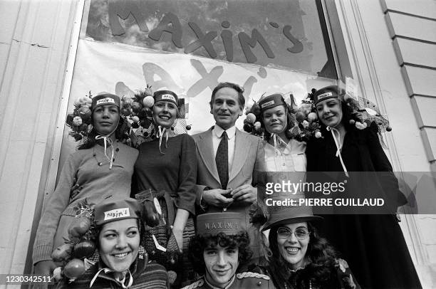 French designer Pierre Cardin is surrounded by "Catherinettes" in front of his new shop Maxim's, 25 November 1977, in Paris. AFP PHOTO PIERRE GUILLAUD