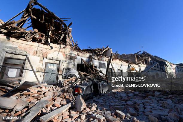 This photograph taken on December 29 shows the wreckage of a car and damaged buildings in Petrinja, some 50kms from Zagreb, after the town was hit by...