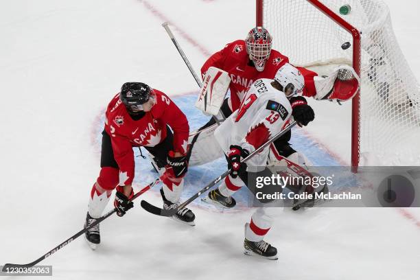 Braden Schneider and goaltender Devon Levi of Canada defend against Valentin Hofer of Switzerland during the 2021 IIHF World Junior Championship at...