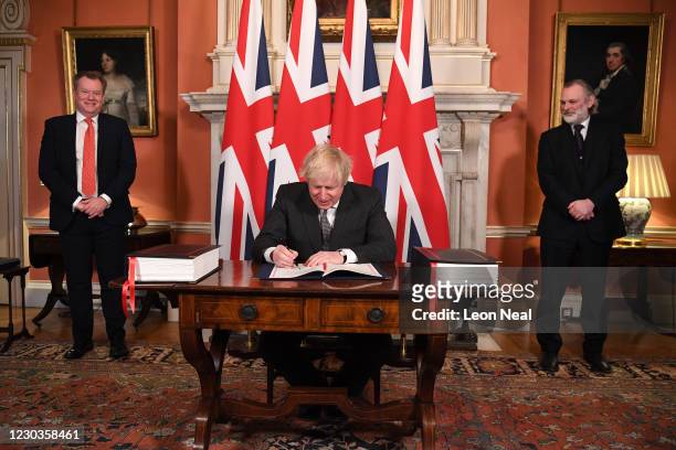 Chief trade negotiator David Frost and British Ambassador to the EU Tim Barrow look on as Prime Minister, Boris Johnson signs the Brexit trade deal...