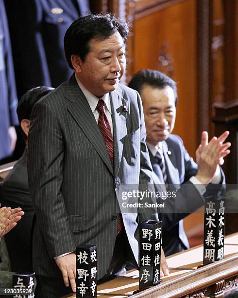 New Democratic Party of Japan President Yoshihiko Noda stands after being elected as Japan's 95th Prime Minister while fellow lawmakers including...