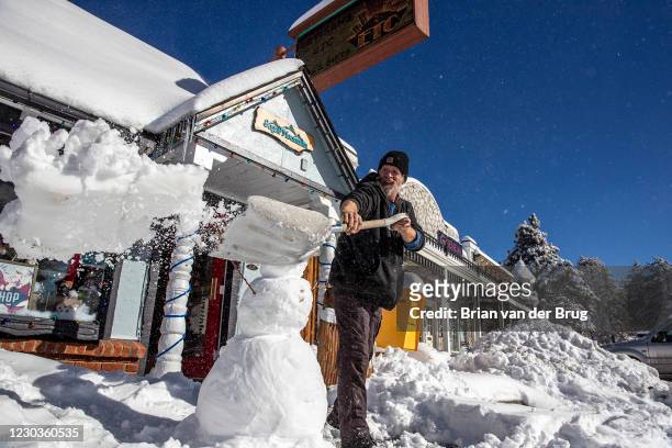 Store owner Adam Hurlbut shovels snow from in from of Sugar Mountain gift store after the nearly a foot of snow fell in the San Bernardino Mountains...