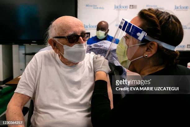 Norman G. Einspruch a cardiology patient at Jackson Memorial Hospital, talks with a nurse after receiving a Pfizer-BioNtech Covid-19 vaccine at...